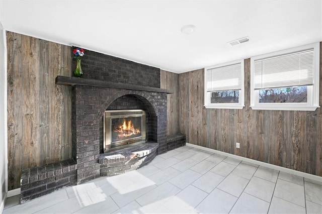 unfurnished living room featuring a fireplace and wood walls