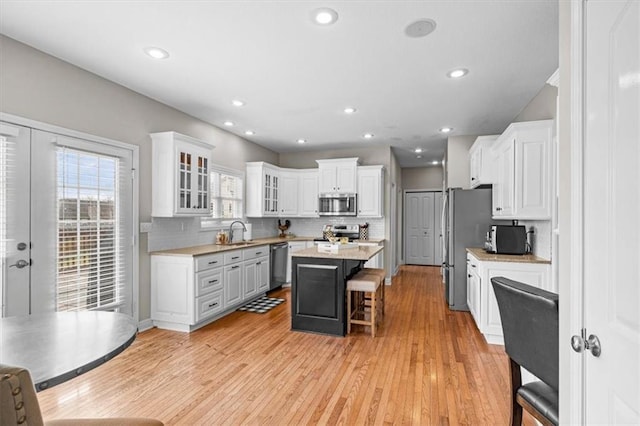 kitchen featuring a kitchen island, appliances with stainless steel finishes, sink, white cabinets, and a kitchen breakfast bar