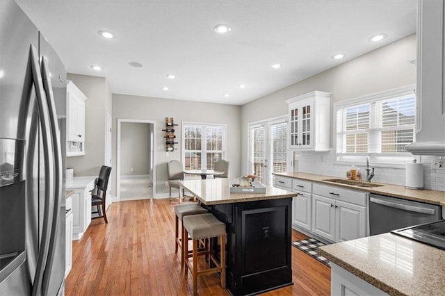 kitchen with white cabinetry, a breakfast bar, a center island, and appliances with stainless steel finishes