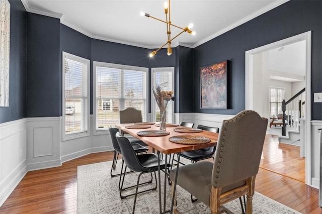 dining space featuring an inviting chandelier, light hardwood / wood-style flooring, and ornamental molding