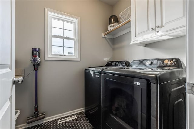 washroom with cabinets, separate washer and dryer, and dark tile patterned floors