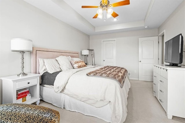 bedroom with light carpet, ceiling fan, and a tray ceiling