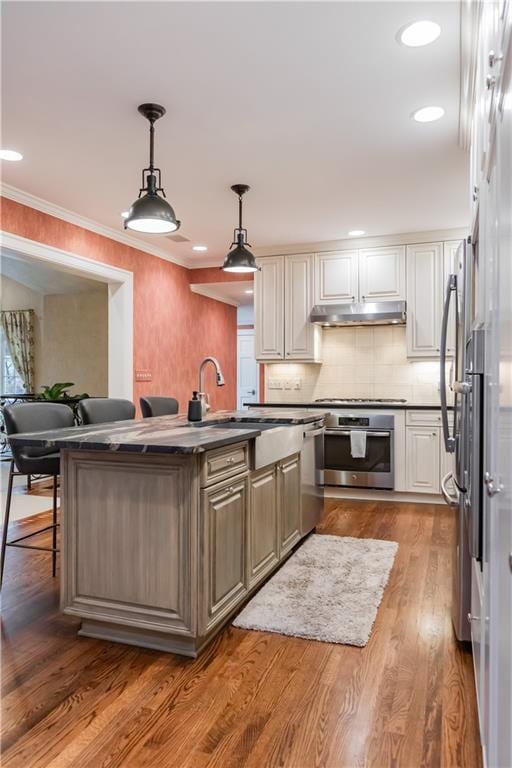 kitchen with decorative light fixtures, cooktop, oven, white cabinets, and a breakfast bar area