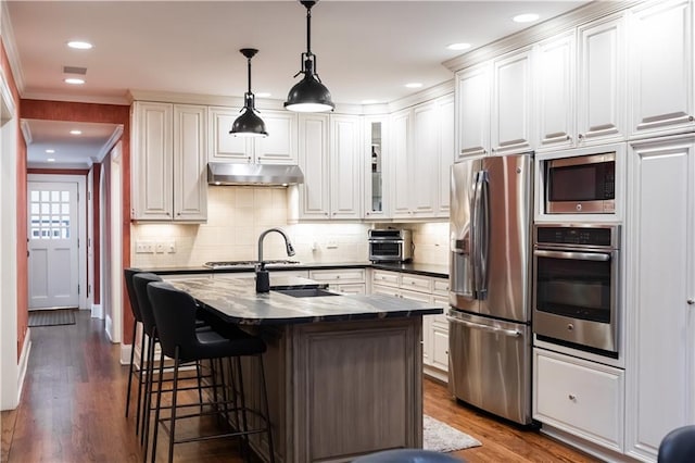 kitchen featuring stainless steel appliances, dark stone counters, crown molding, dark hardwood / wood-style flooring, and white cabinetry