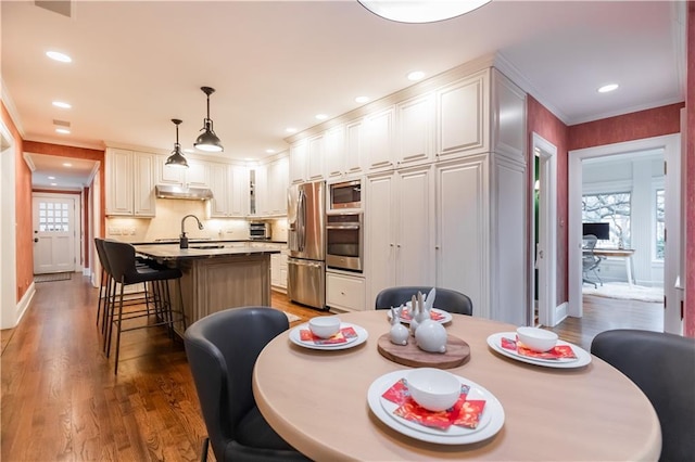 dining space with sink, ornamental molding, and dark wood-type flooring