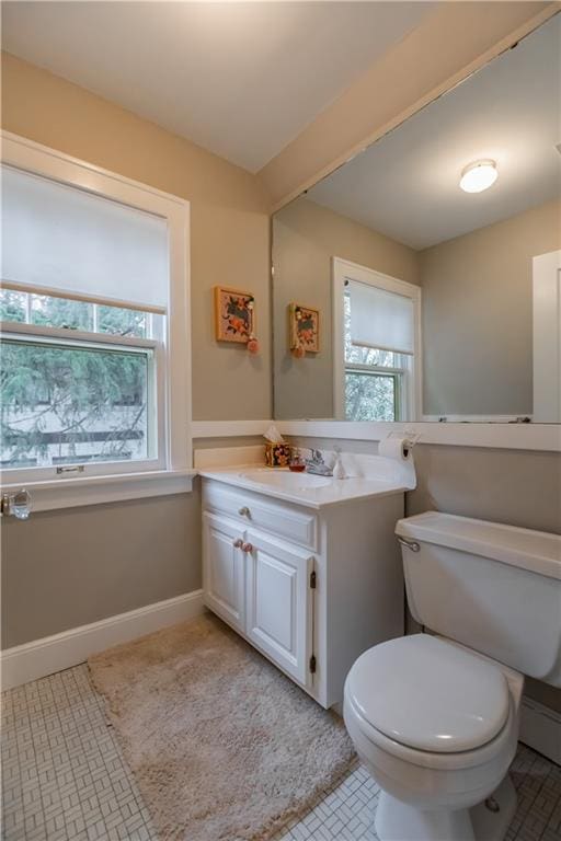 bathroom with toilet, vanity, and tile patterned flooring