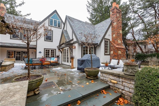 rear view of house with a patio area, french doors, and an outdoor living space with a fireplace