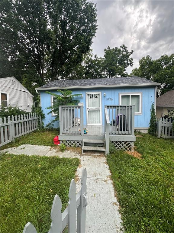 back of property with a wooden deck and a lawn