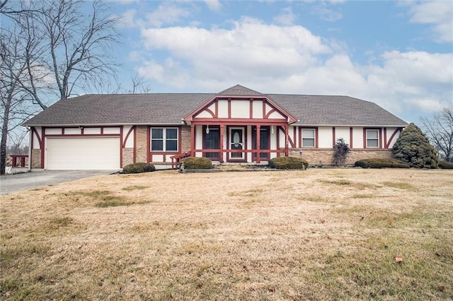 tudor house with a garage, a front yard, and a porch