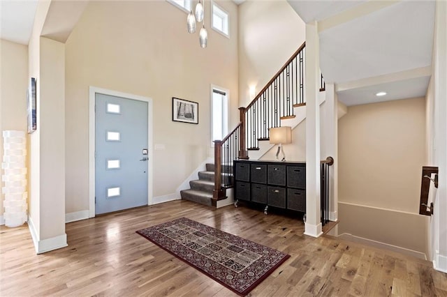 foyer with baseboards, stairs, a towering ceiling, and wood finished floors