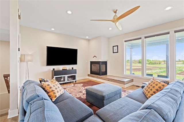 living area with plenty of natural light, baseboards, ceiling fan, and wood finished floors
