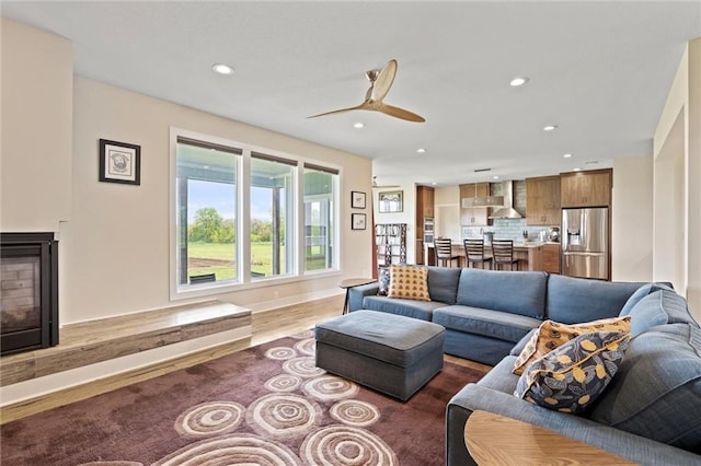 living area featuring recessed lighting, ceiling fan, wood finished floors, and a fireplace