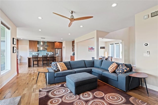 living area with light wood-style floors, baseboards, ceiling fan, and recessed lighting