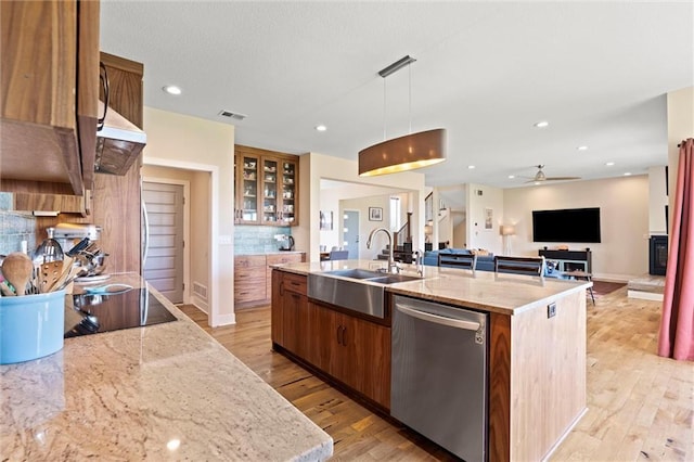 kitchen with stainless steel dishwasher, visible vents, an island with sink, light wood-type flooring, and a sink