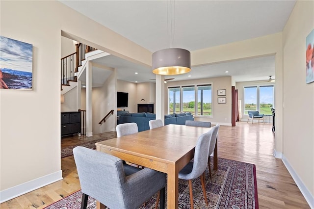 dining room with baseboards, stairway, and light wood-style floors