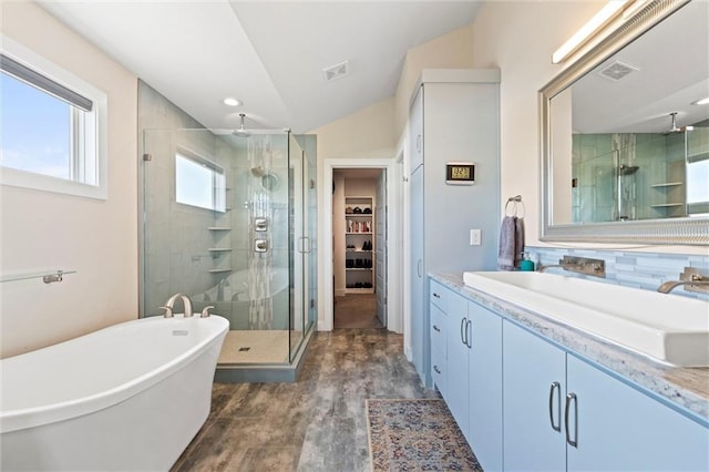 bathroom featuring a walk in closet, vanity, a shower stall, wood finished floors, and visible vents