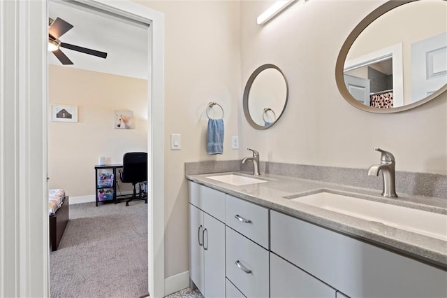 bathroom with baseboards, double vanity, ceiling fan, and a sink