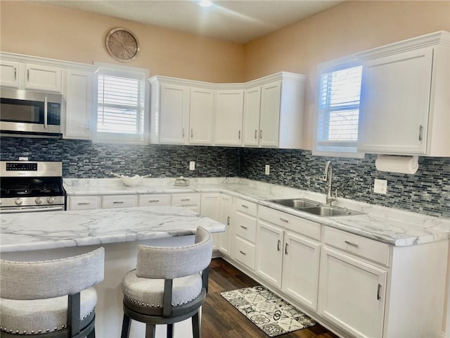 kitchen with white cabinetry, appliances with stainless steel finishes, a kitchen bar, and sink