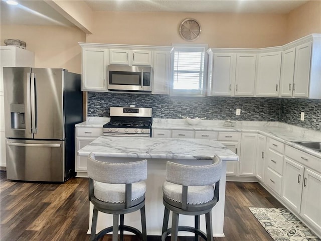 kitchen featuring light stone countertops, a breakfast bar area, stainless steel appliances, and white cabinets