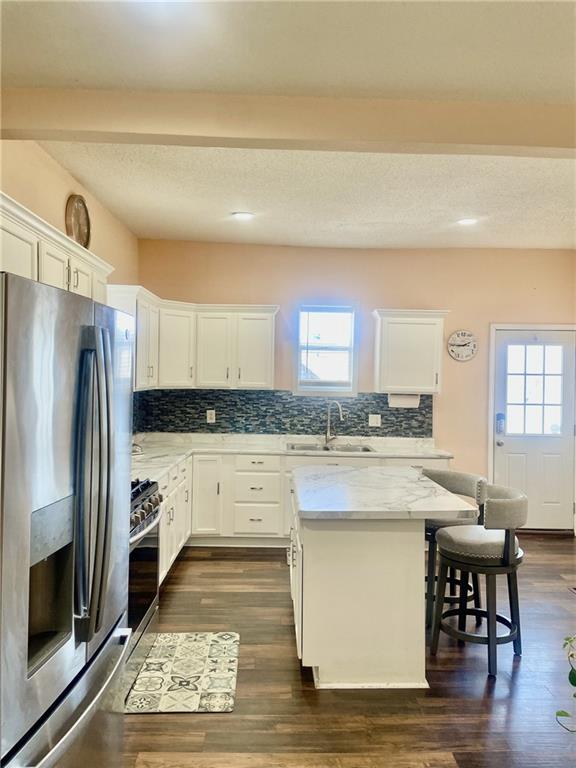 kitchen featuring sink, a center island, stainless steel appliances, light stone countertops, and white cabinets