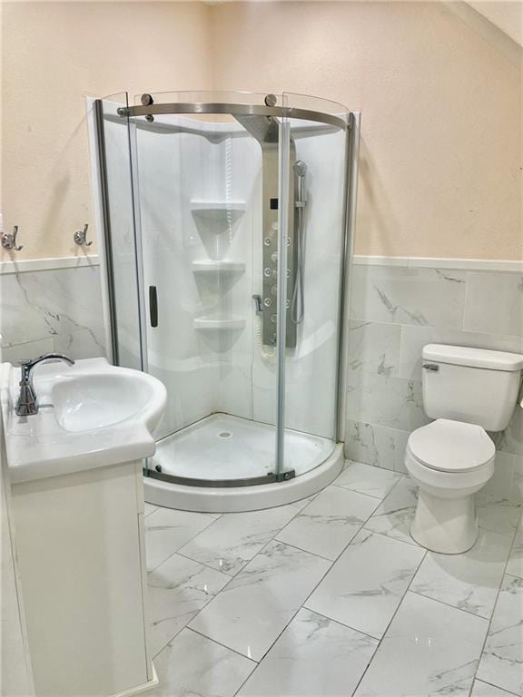 bathroom featuring a shower with door, vanity, tile walls, and toilet