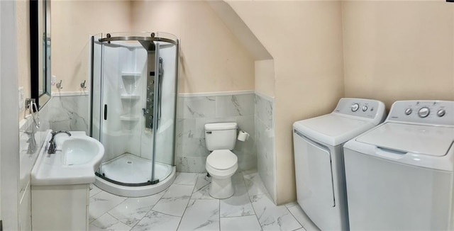 bathroom featuring sink, tile walls, washing machine and clothes dryer, a shower with shower door, and toilet