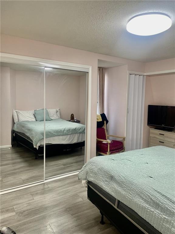 bedroom featuring a textured ceiling, a closet, and light hardwood / wood-style flooring