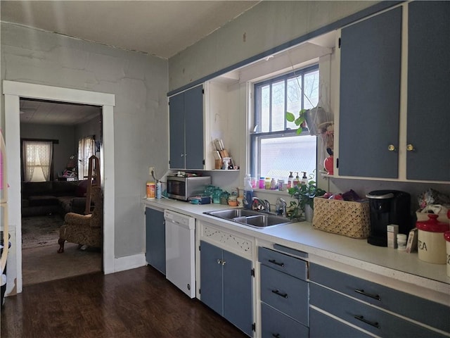 kitchen featuring white dishwasher, sink, dark wood-type flooring, and blue cabinets