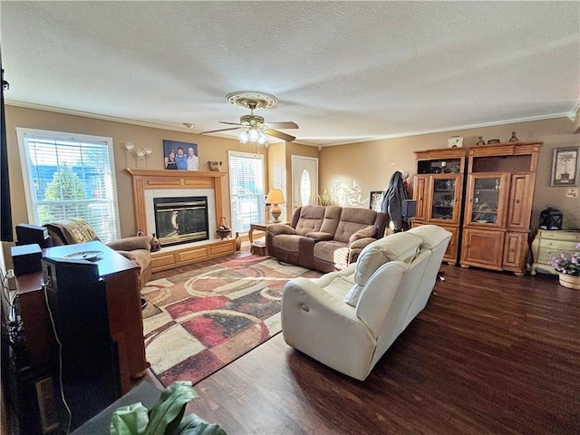 living area with a textured ceiling, ornamental molding, a tiled fireplace, and wood finished floors