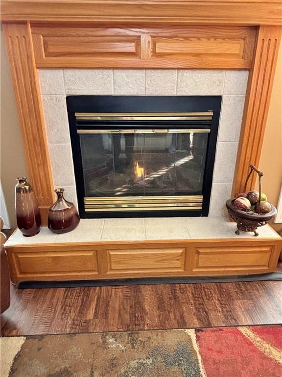 details with a tiled fireplace and wood finished floors