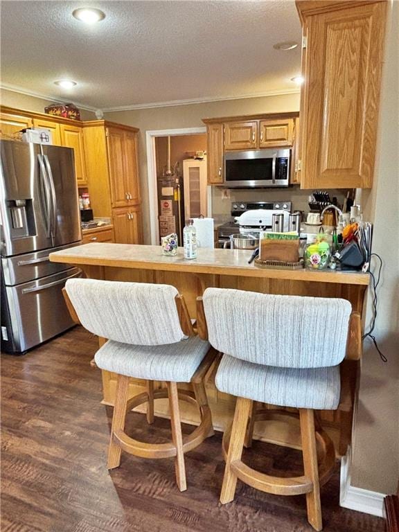 kitchen featuring dark wood-style floors, ornamental molding, a peninsula, stainless steel appliances, and water heater