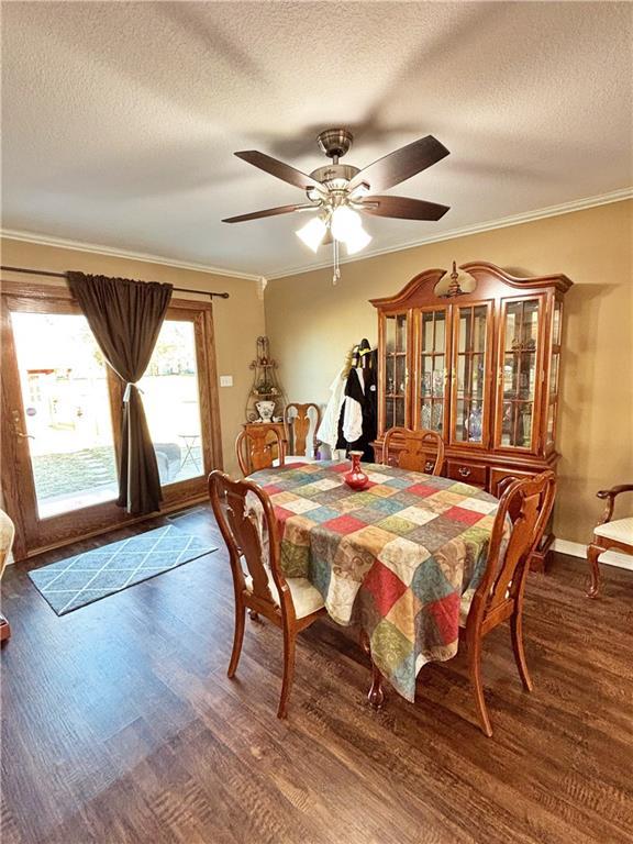 dining space featuring ornamental molding, dark wood-type flooring, and a ceiling fan