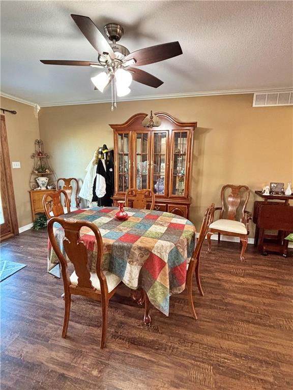 dining area featuring visible vents, a ceiling fan, ornamental molding, wood finished floors, and a textured ceiling