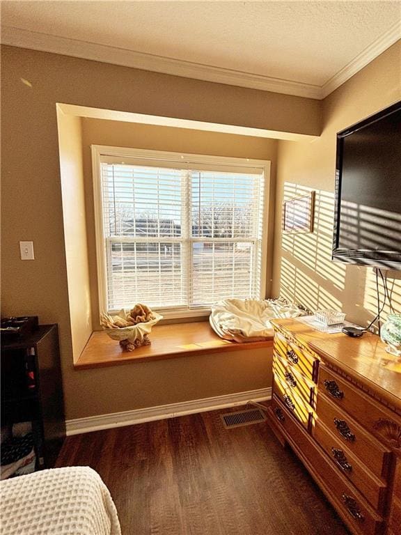 bedroom with baseboards, a textured ceiling, ornamental molding, and wood finished floors