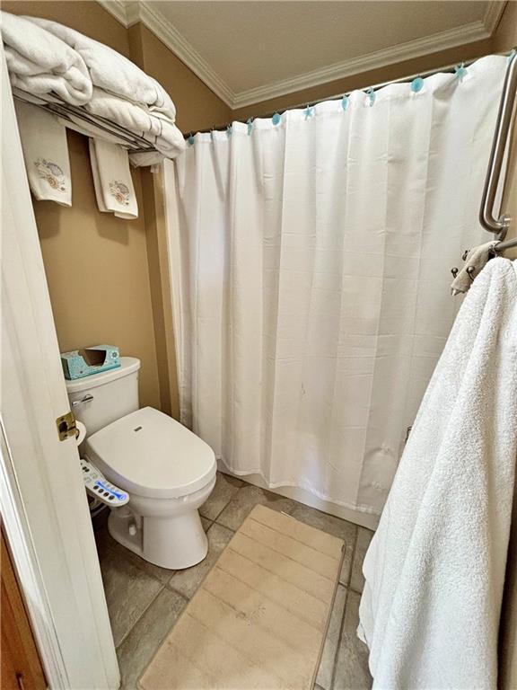 bathroom featuring toilet, curtained shower, and ornamental molding