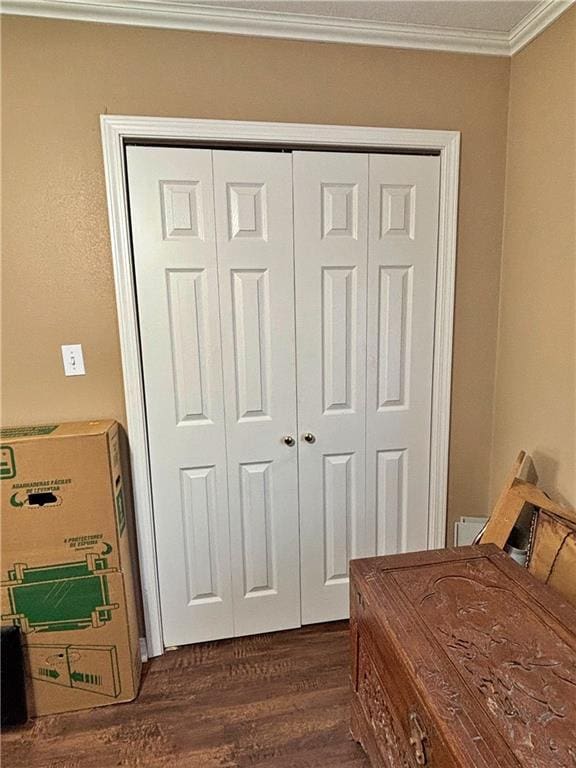 bedroom with dark wood-style flooring, a closet, and crown molding