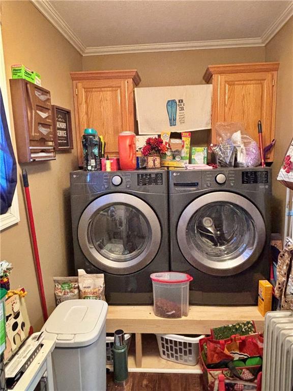 laundry area featuring ornamental molding, washer and dryer, radiator, and cabinet space