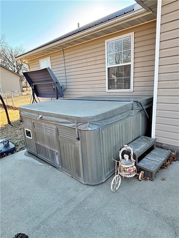 view of patio / terrace featuring a hot tub and fence