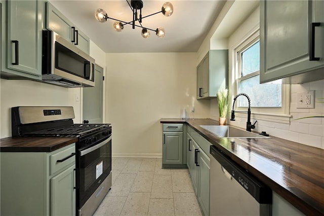 kitchen featuring an inviting chandelier, wood counters, stainless steel appliances, and sink