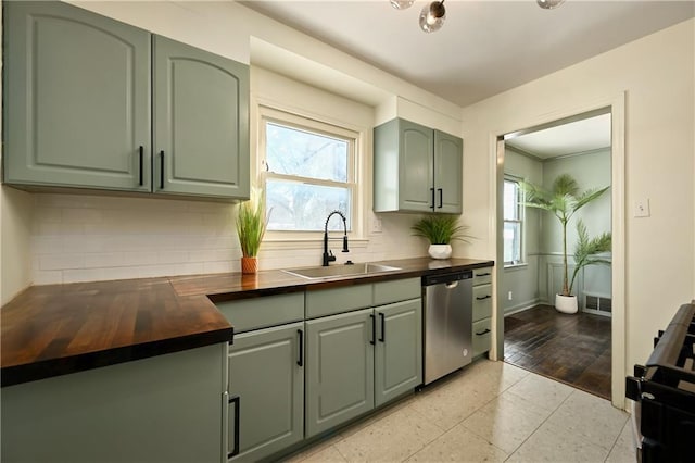 kitchen with sink, green cabinets, butcher block counters, range, and stainless steel dishwasher