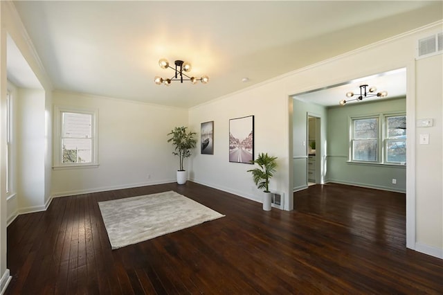 empty room with dark wood-type flooring, plenty of natural light, crown molding, and a chandelier