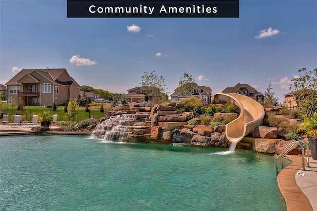 community pool featuring a water slide, fence, and a residential view