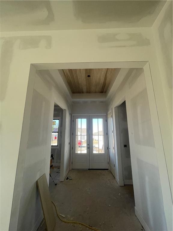 interior space featuring wooden ceiling, a tray ceiling, and french doors