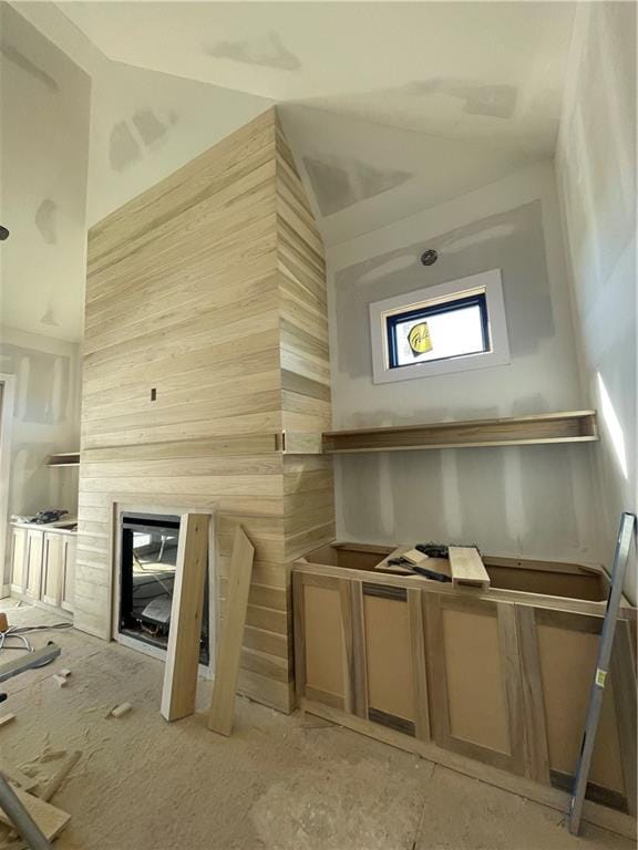 interior space with a glass covered fireplace and lofted ceiling