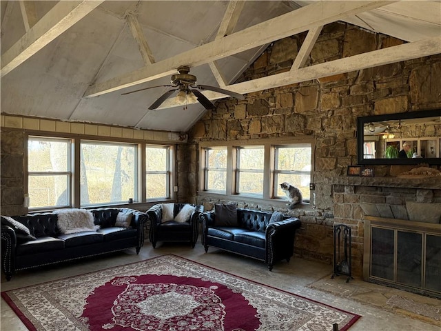 living room featuring ceiling fan, a stone fireplace, and lofted ceiling with beams