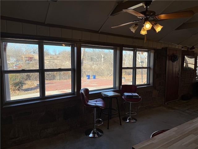 dining space with wooden walls and ceiling fan