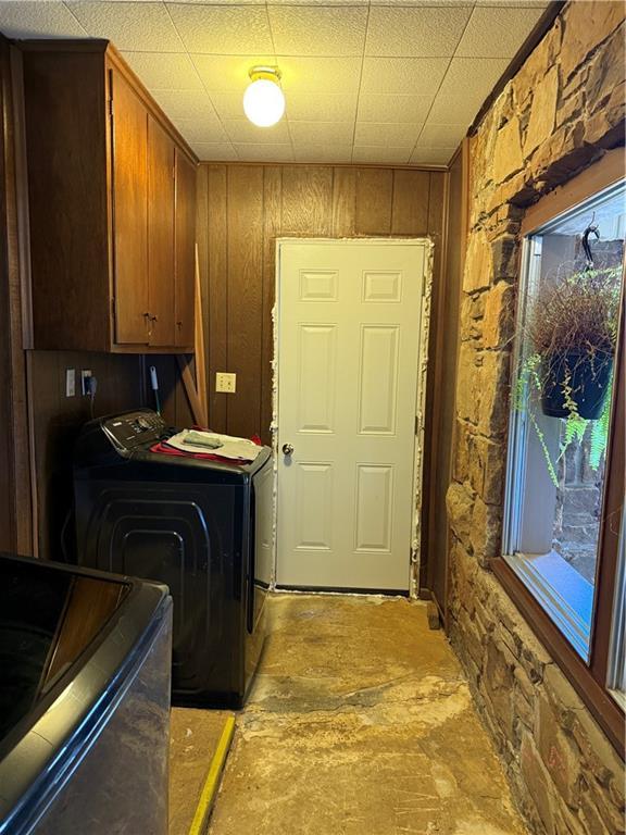 laundry room featuring washer and clothes dryer, cabinets, and wooden walls