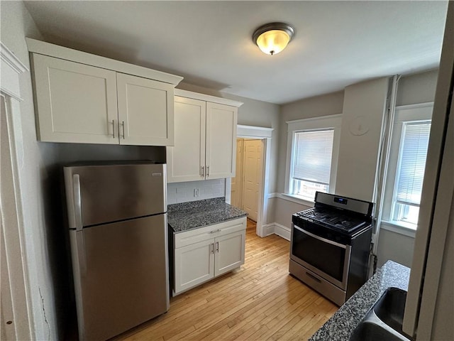 kitchen featuring white cabinetry, decorative backsplash, appliances with stainless steel finishes, and light hardwood / wood-style flooring