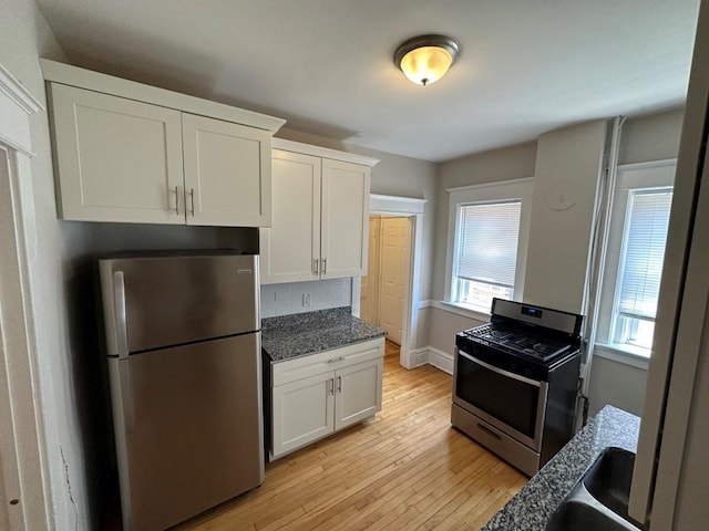 kitchen with decorative backsplash, stainless steel appliances, light hardwood / wood-style floors, and white cabinets