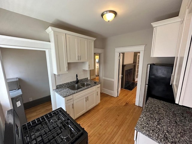 kitchen featuring stainless steel refrigerator, tasteful backsplash, sink, white cabinets, and light wood-type flooring